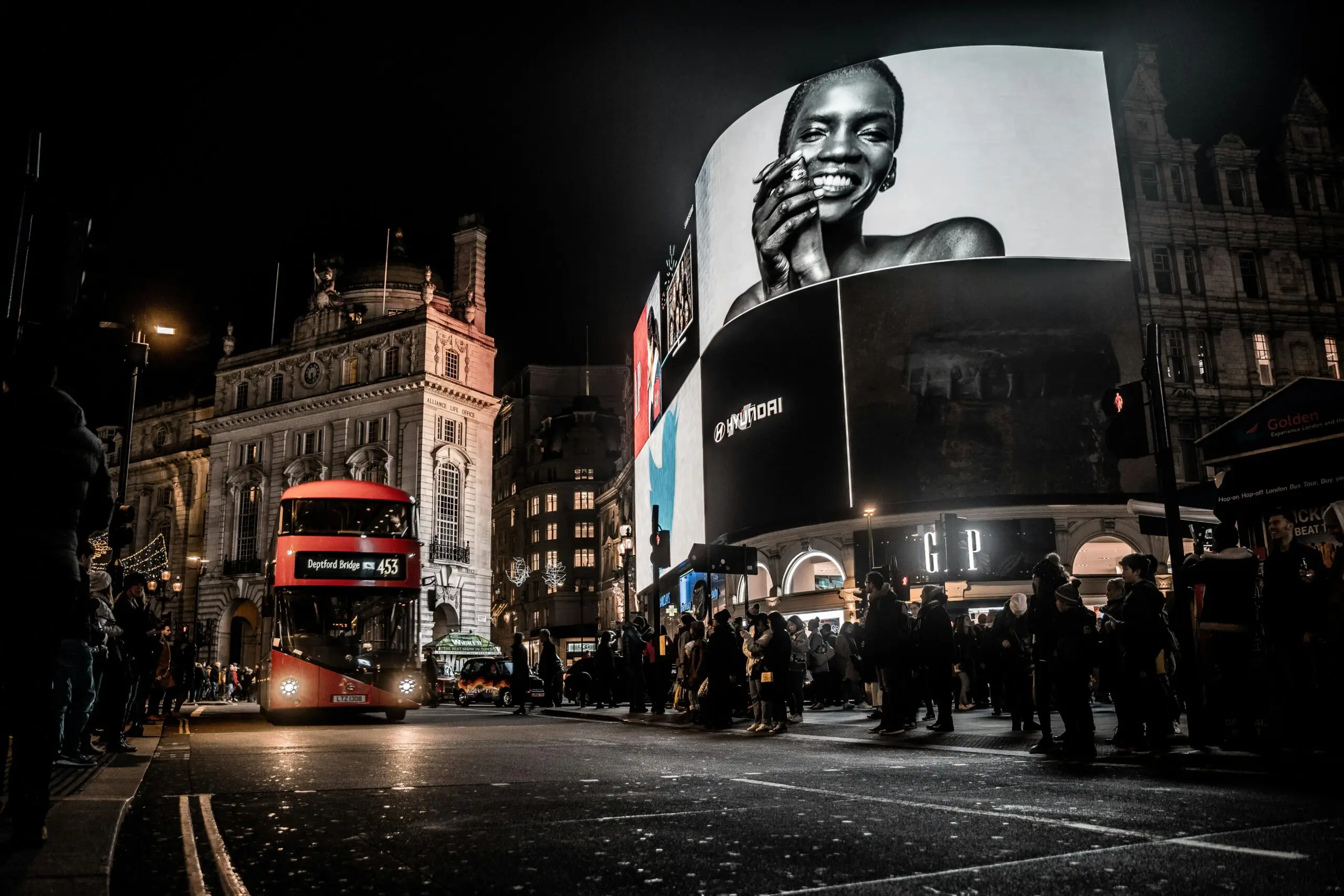 A vibrant city night scene with bright digital billboards and a red bus, showcasing the expertise of a Freelance Digital Marketing Strategist in Kochi in running effective digital ad campaigns.