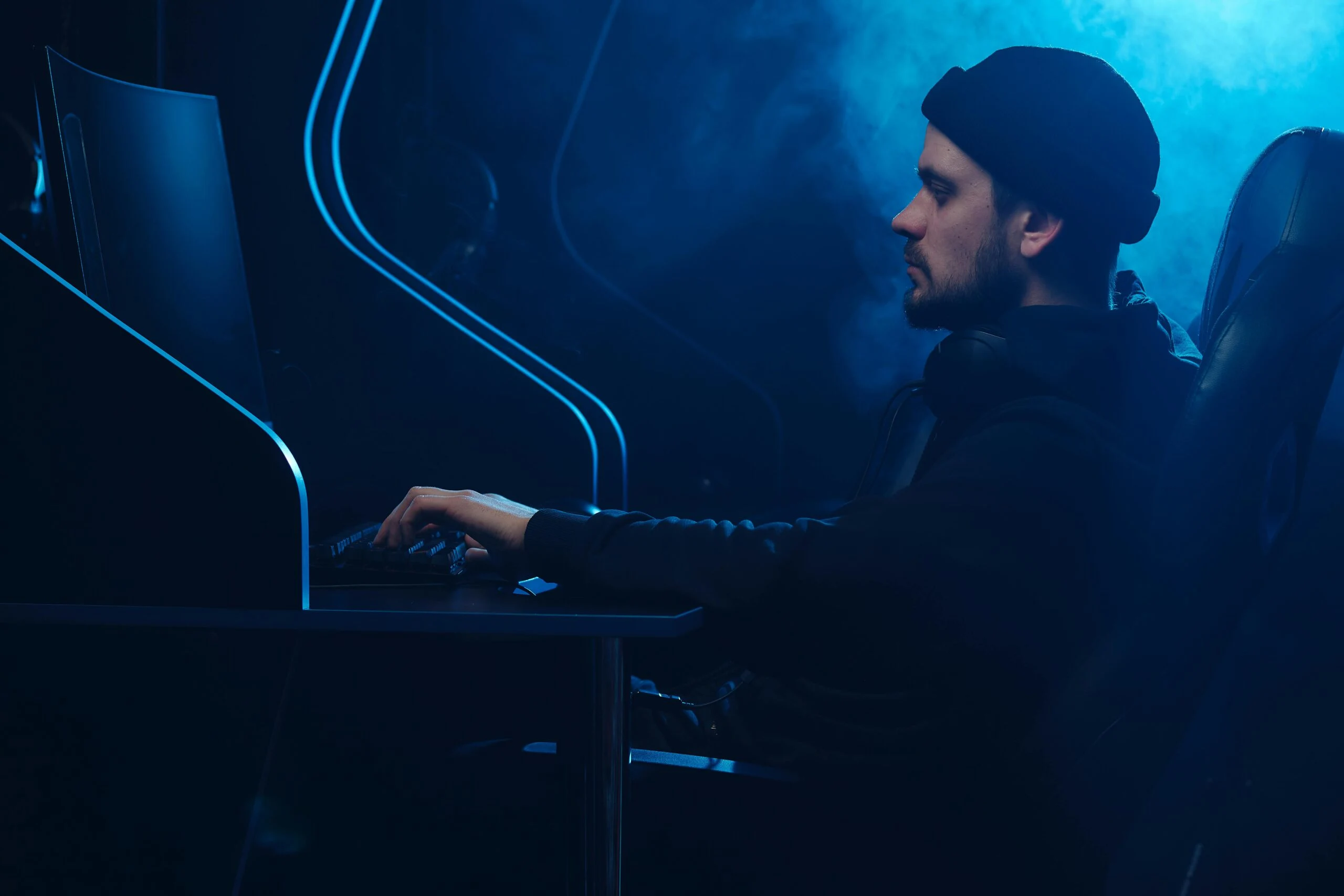 A person focused on a computer screen in a dark, blue-lit room, representing the technical and strategic web development services offered by a Freelance Digital Marketing Strategist in Kochi.